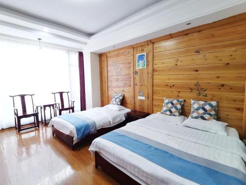 a bedroom with two beds and a wooden wall at Emeishan Moon Bay Hotel in Emeishan