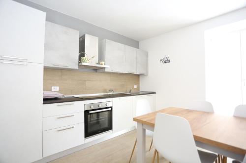 Casa BEA 1 في كاستوني ديلا بريسولانا: مطبخ بخزائن بيضاء وطاولة خشبية