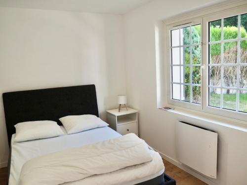 a white bedroom with a bed and a window at Villa Les Rosiers private parking in Le Touquet-Paris-Plage