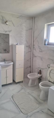 a white bathroom with a toilet and a sink at Casa Bella in Cicanesti