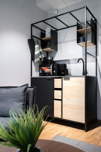 a kitchen with black and wooden cabinets in a living room at Brand new Kalma Apartments in Tallinn