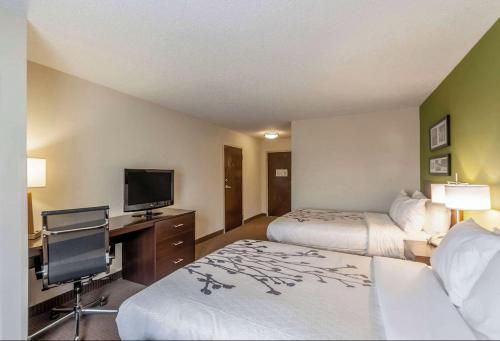 a hotel room with two beds and a desk with a television at Sleep Inn & Suites Harrisonburg near University in Harrisonburg