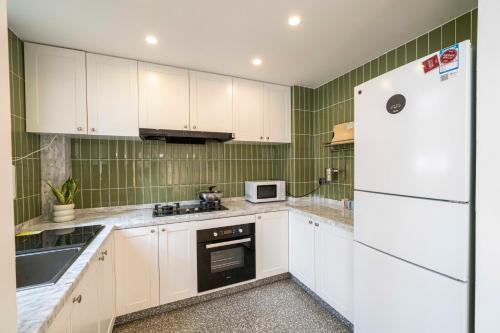 a kitchen with white cabinets and a white refrigerator at Book and Bed-People's Square in Shanghai