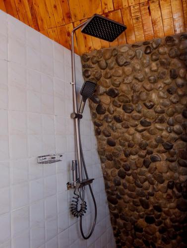 a shower in a bathroom with a stone wall at Kaasham Cabin Nanyuki in Nanyuki