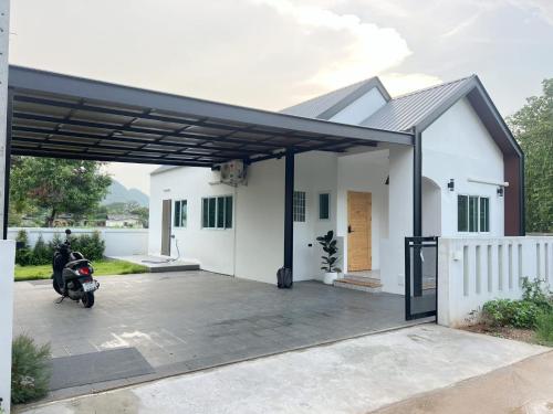 a garage with a scooter parked in front of a house at Cheeva Home in Ban Pa Tung (7)