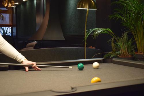 a person playing a game of pool on a table at Le Trophée Boutique Hôtel Spa- La Loggia Appart'hôtel in Deauville