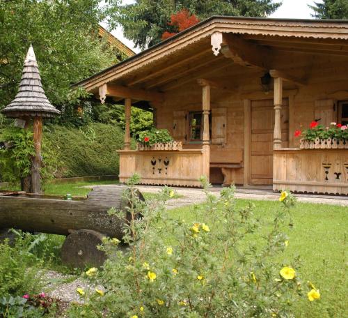 a wooden house with a porch and a garden at Pension Wolfsegg in Kirchberg in Tirol