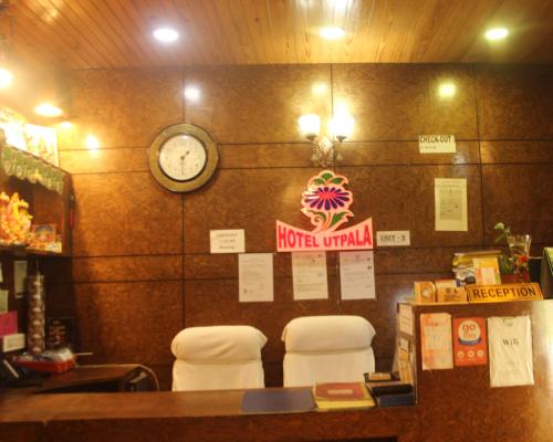 a restaurant with two chairs and a clock on the wall at Hotel Utpala in Gangtok
