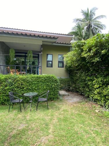 een tafel en twee stoelen voor een huis bij Green & Pink Garden Homes in Ko Phangan