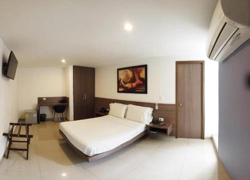 a bedroom with a large white bed and a desk at Hotel Mio Boutique in Cúcuta
