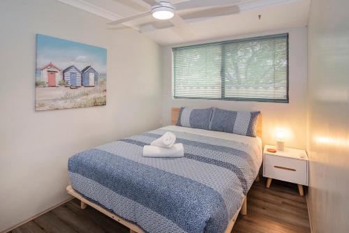 a bedroom with a bed with a blue blanket and a window at Just Chillin- Pool, 2km to beach in Broadwater