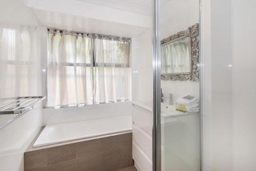 a white bathroom with a shower and a sink at Just Chillin- Pool, 2km to beach in Broadwater