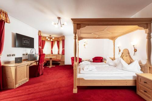 a bedroom with a canopy bed and a desk at Hotel La Perla Wellness & Beauty in Canazei