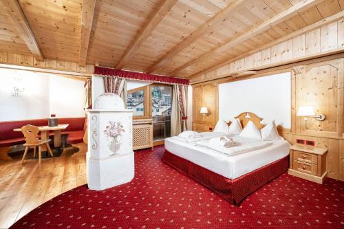 a bedroom with a bed and a desk in a room at Hotel La Perla Wellness & Beauty in Canazei