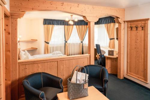 a room with a bed and a table and chairs at Hotel La Perla Wellness & Beauty in Canazei