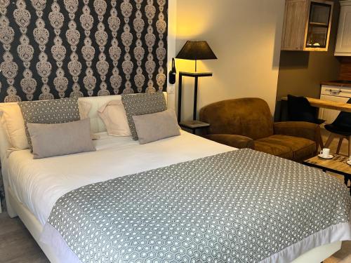 a bedroom with a large bed and a chair at Le Trophée Boutique Hôtel Spa- La Loggia Appart'hôtel in Deauville