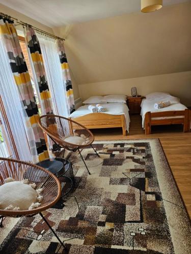 a room with two beds and two chairs and a rug at Wynajem pokoi Natalia in Sromowce Niżne