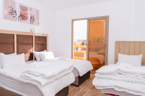 two beds in a room with white sheets at Tifawine Stay Guest House Social Stay and Oceanview Rooms in Imsouane
