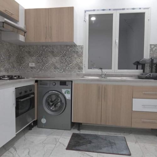 a kitchen with a sink and a washing machine at اقامة بيرم Résidence Bayrem in Houmt Souk