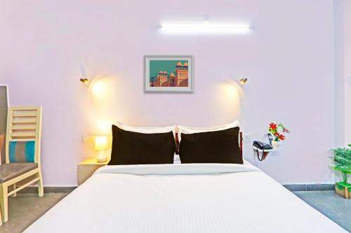 a bedroom with a white bed and a chair at Collection O De Alphabet Hotel UMCC in Hyderabad