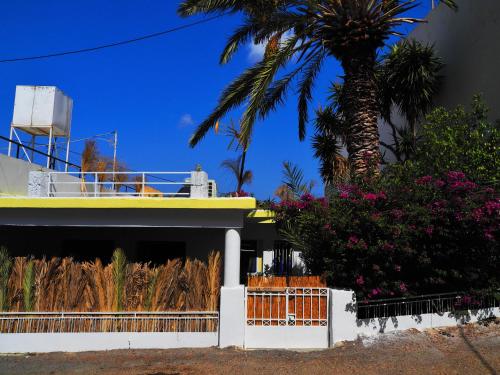 a palm tree in front of a house with a fence at Le Gîte in Sitia