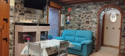 ein Wohnzimmer mit einem blauen Sofa und einem Tisch in der Unterkunft EL PICO Casa en plena naturaleza con vistas espectaculares in Arredondo