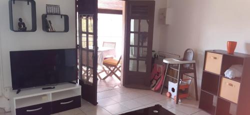 a living room with a flat screen tv next to a door at Petit F2 en campagne au Vauclin in Le Vauclin