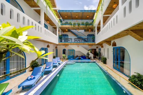 an indoor pool with blue lounge chairs and a swimming pool in a building at The Linh Coastline Villa in Hoi An