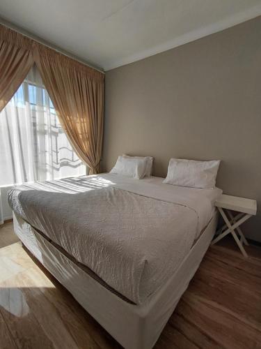 a bed in a bedroom with a large window at Mont Pelaan 88 in Newcastle