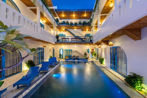 an indoor pool in a building with blue chairs at The Linh Coastline Villa in Hoi An