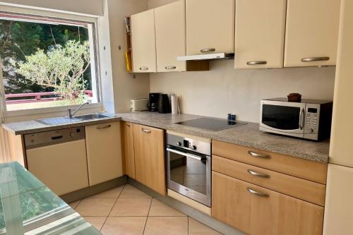 a kitchen with wooden cabinets and a microwave and a window at Appartement Lakeside in Hossegor