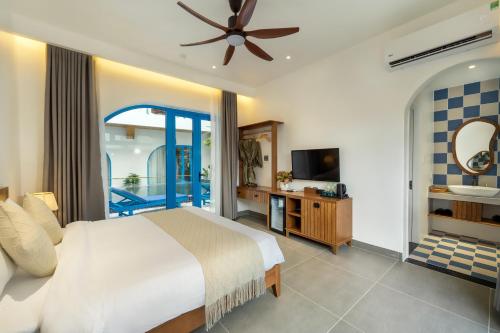 a bedroom with a bed and a tv and a balcony at The Linh Coastline Villa in Hoi An