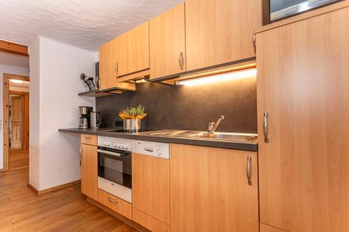 a kitchen with wooden cabinets and a sink at Gästehaus Dreier in Neukirchen am Großvenediger