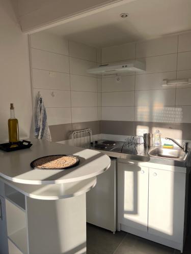 une cuisine blanche avec un comptoir et un évier dans l'établissement Cosy Studio hyper centre avec kitchenette & Climatisation, à Carpentras
