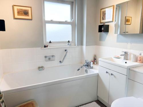 a white bathroom with a tub and a sink at Cosy whole home in central Faversham in Kent