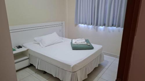 a white bed with a purse on top of it at Rivello Apart Hotel in Sete Lagoas