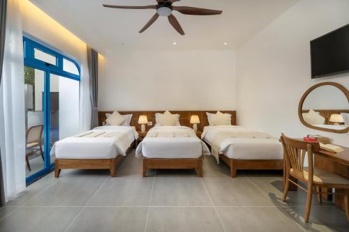 a bedroom with three beds and a ceiling fan at The Linh Coastline Villa in Hoi An