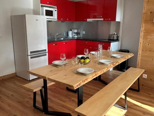 une table en bois dans une cuisine avec des placards rouges dans l'établissement Spacieux appart rénové, 3 pièces + cabine, proche pistes, 8 pers, animaux admis - FR-1-181-1913, à La Plagne Tarentaise