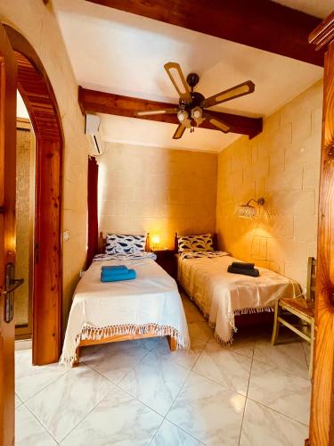 a bedroom with two beds and a ceiling fan at See You Mystic Flowers in Għarb