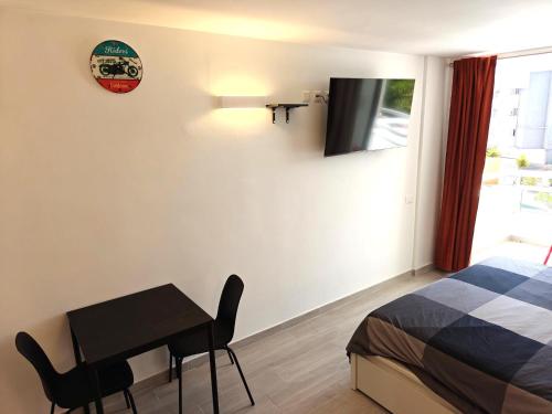 Un dormitorio con una cama, un escritorio y un televisor. en RUBIK's studio, lovely Las Americas, en Costa de Adeje