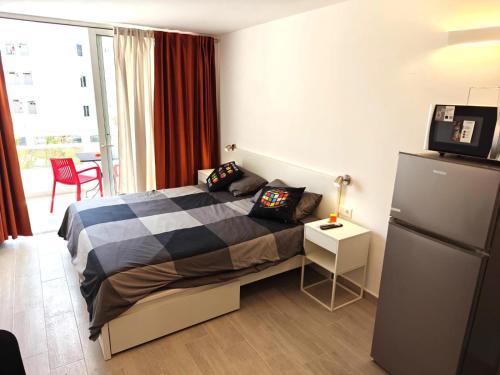 Un dormitorio pequeño con una cama y un refrigerador. en RUBIK's studio, lovely Las Americas, en Costa de Adeje