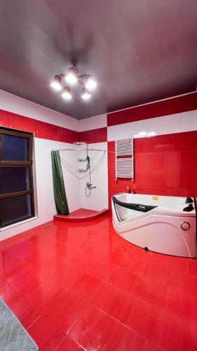 a red bathroom with a white tub and a red floor at дом в Махинджаури in Makhinjauri