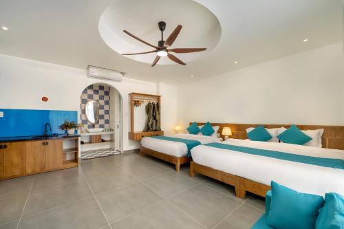 a bedroom with two beds and a ceiling fan at The Linh Coastline Villa in Hoi An