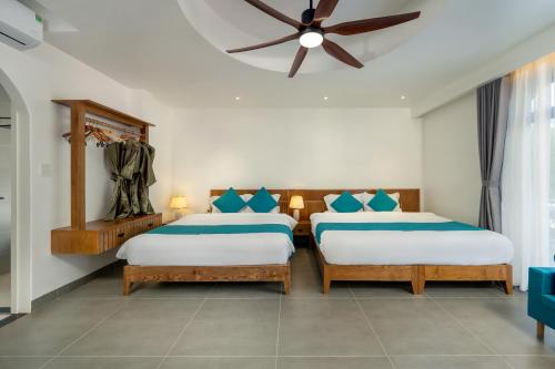 two beds in a room with a ceiling fan at The Linh Coastline Villa in Hoi An
