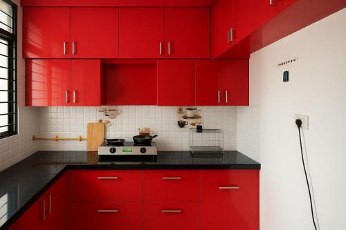 a red kitchen with black counters and red cabinets at Bright space for fun in Bhopal