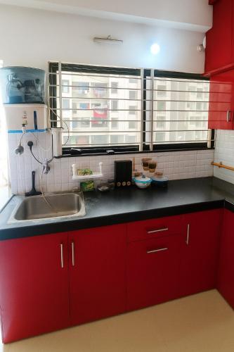 a kitchen with red cabinets and a sink at Bright space for fun in Bhopal