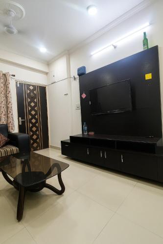 a living room with a flat screen tv and a chair at Bright space for fun in Bhopal