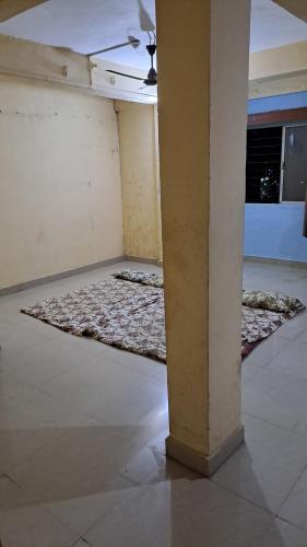 an empty room with a pillar and a rug at Sangita Lodge in Ratnagiri