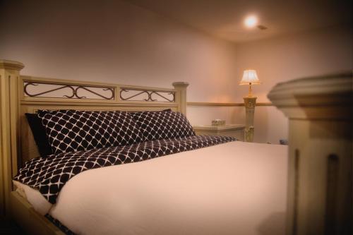 a bed with a black and white pillow and a lamp at Spacious vintage styled basement apartment - private in Calgary