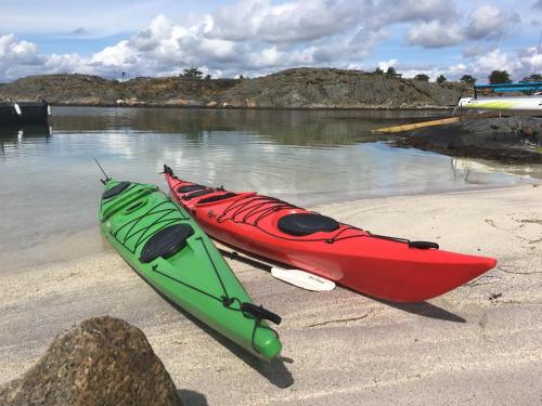 two kayaks sitting on a beach next to the water at Pollyville in Lillesand
